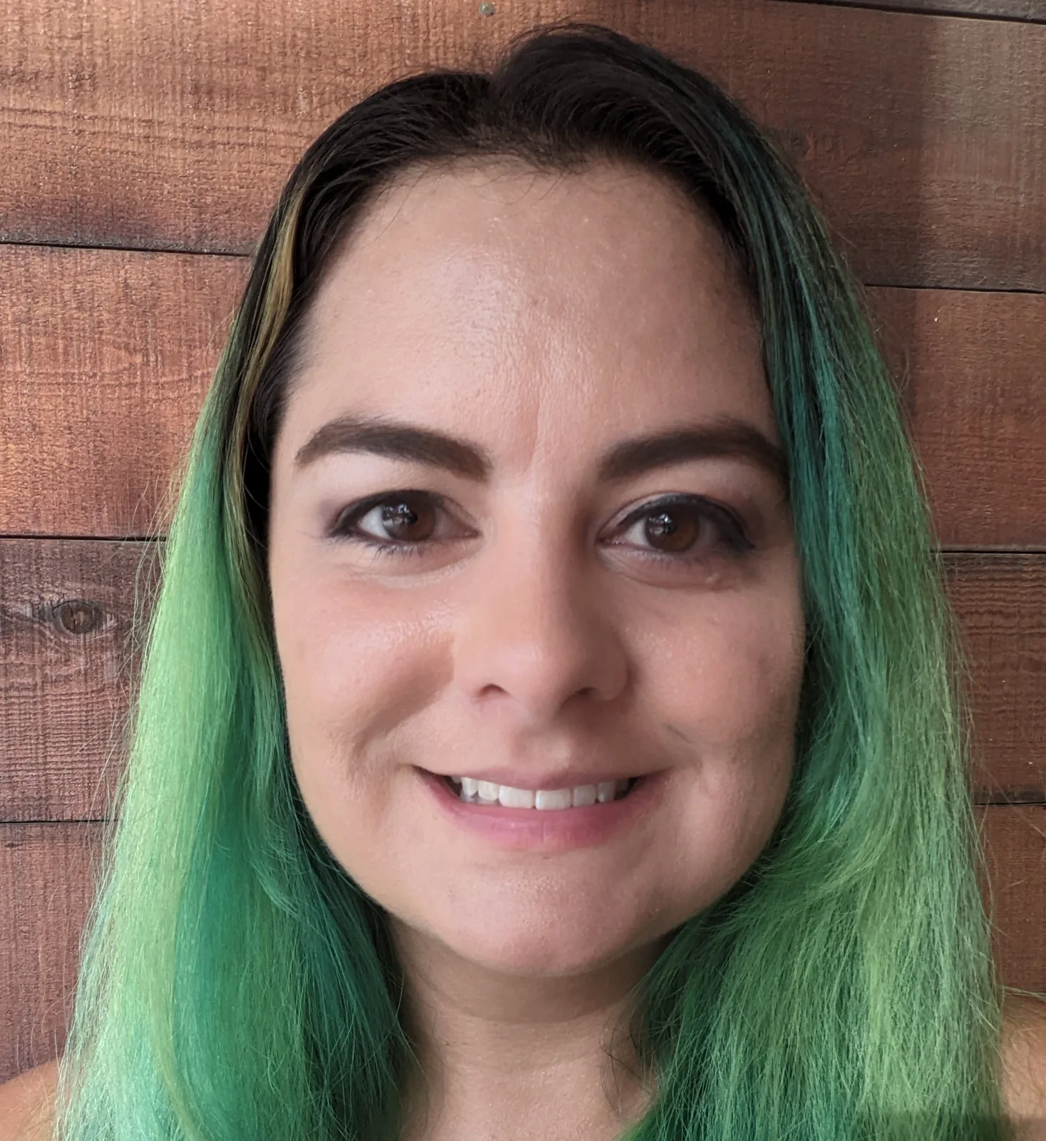 Portrait of Abigail Axness smiling, with long green-tinted hair