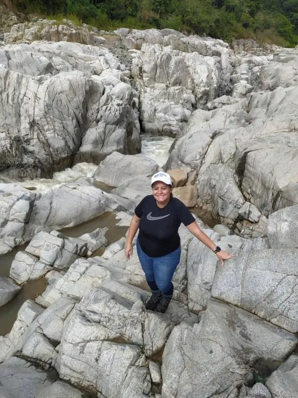 Abigail standing on pale, water-sculpted bedrock in a river channel