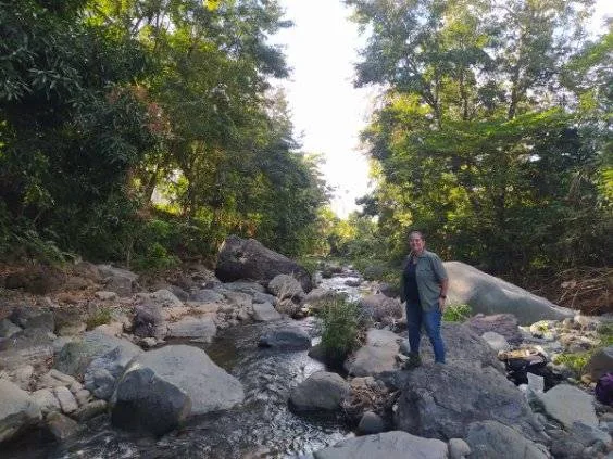 Abigail standing among large boulders in a forested stream channel