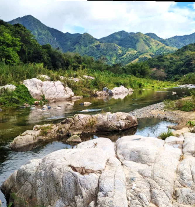 Clear river winding past rounded white bedrock boulders with green mountains behind